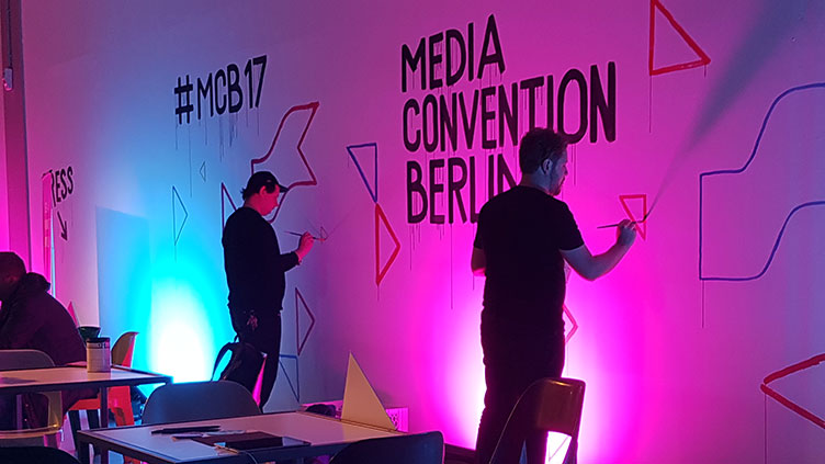 Eine Wand auf der re:publica wird bemalt. Zu sehen sind die Schriftzüge #mcb14 und Media Convention Berlin.